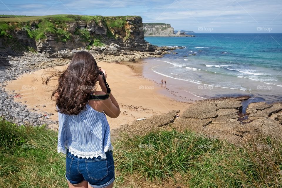 Teenage girl takes photos of a beautiful beach