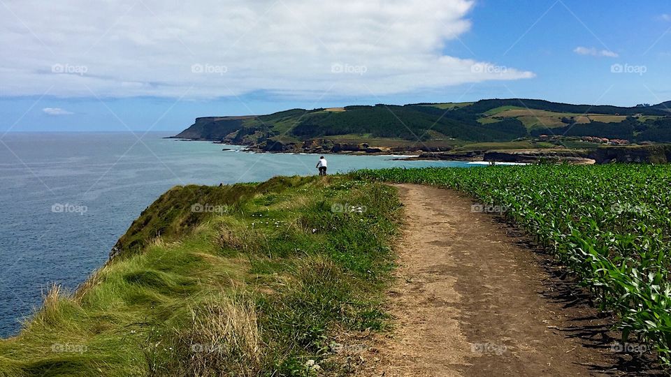 A man riding a bike on the coastline path at Cantabria, Spain 