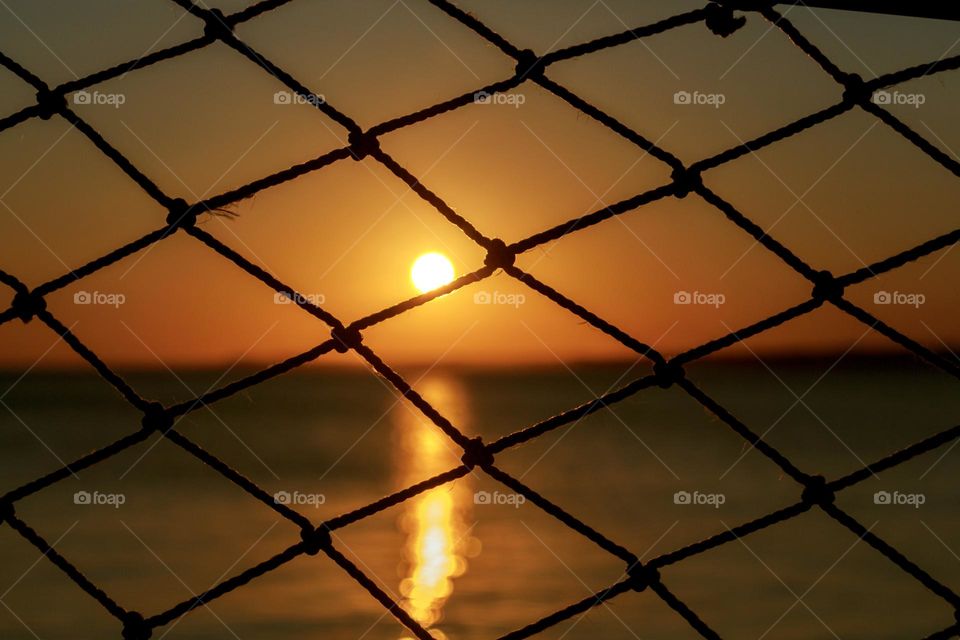 Beautiful sunset over the sea through the net 