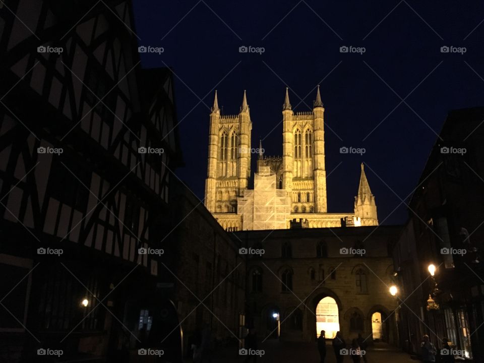 View of Exchequergate in Lincoln at night with lincoln cathedral illuminated behind the stone archway