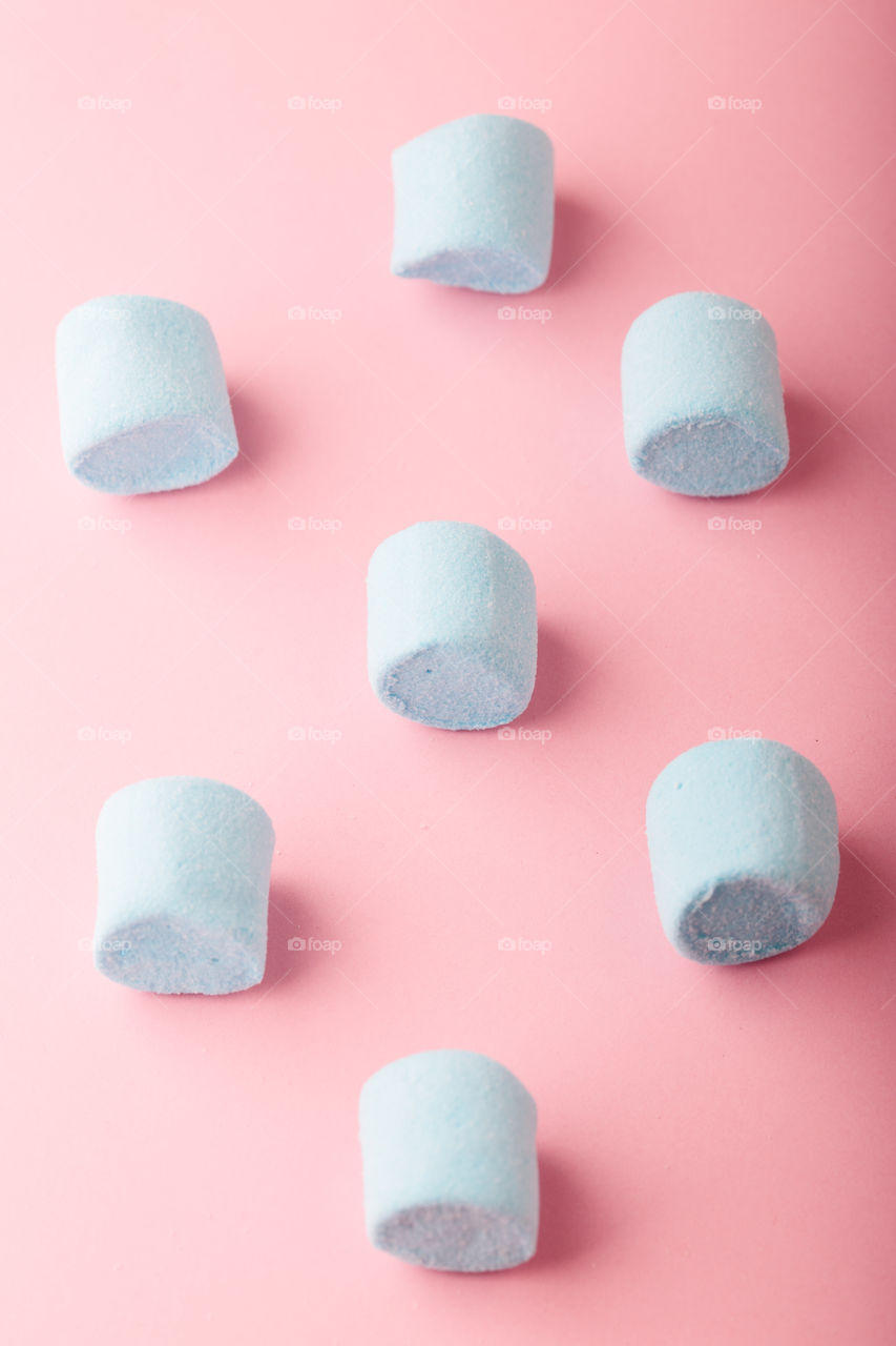 Pattern of blue marshmallows on plain pink background