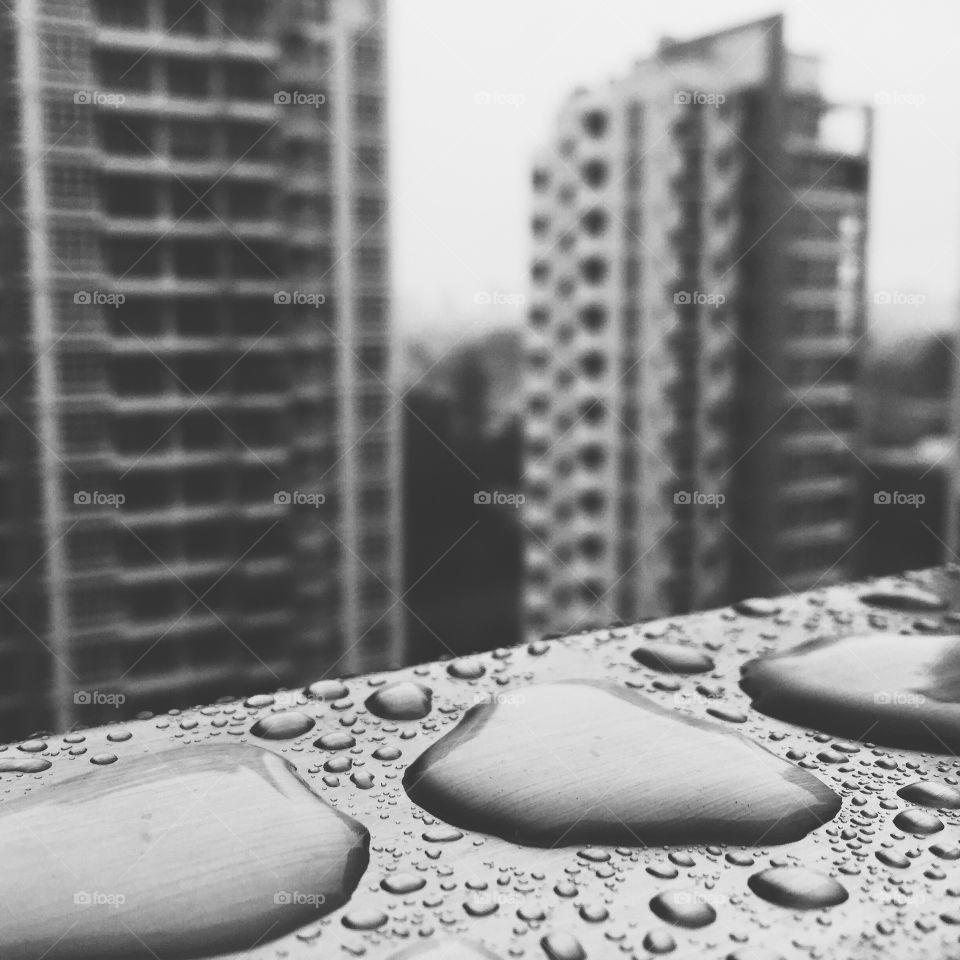 Raindrops accumulate at the stainless steel railing of a high rise building 
