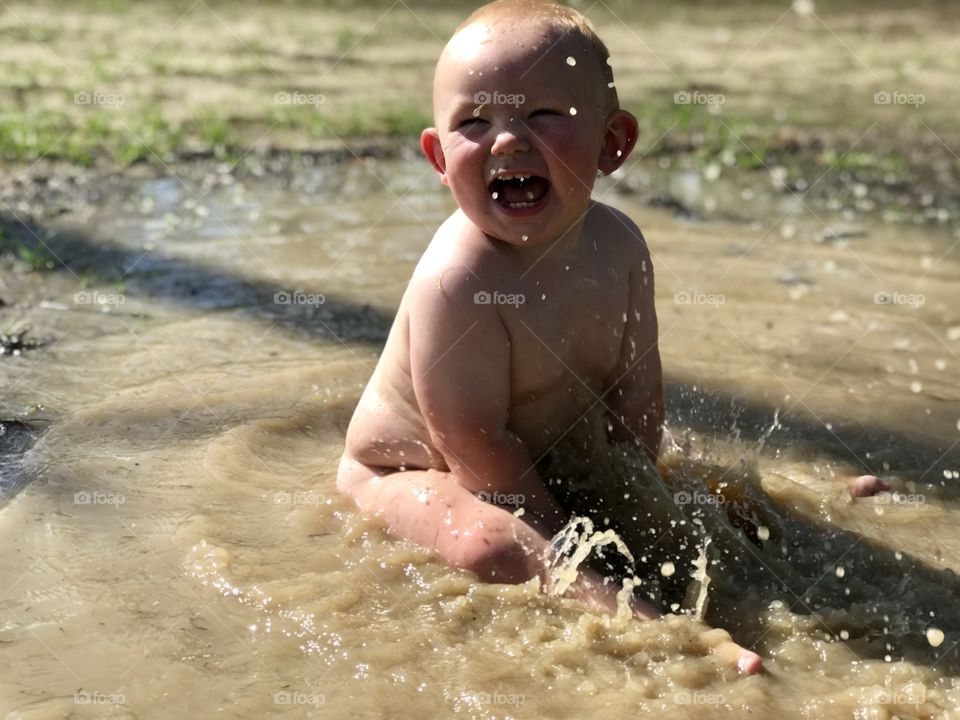 Toddler playing mud puddle 
