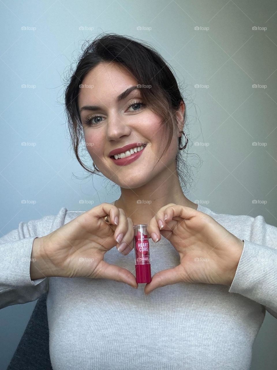 Woman’s portrait with product, girl holding a lipstick in her hands 