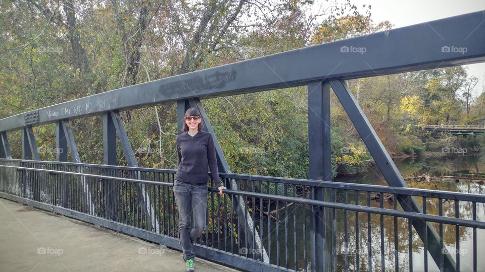 Woman with sunglasses standing on bridge