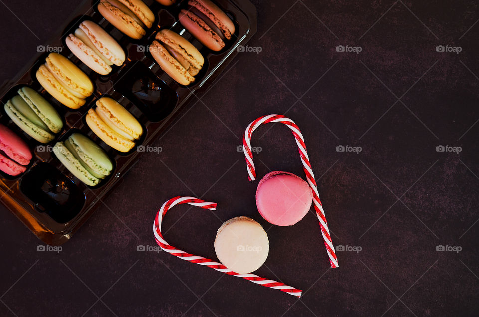 Background of the colorful delicious macaroons at dark table close up. Valentine's day. Greetings card. Flat lay.