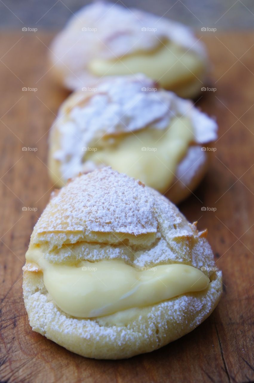 Vanilla filled cream puffs on cutting board