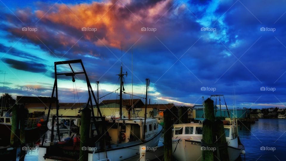coastal living. the beautiful sky illuminates the lobster boats