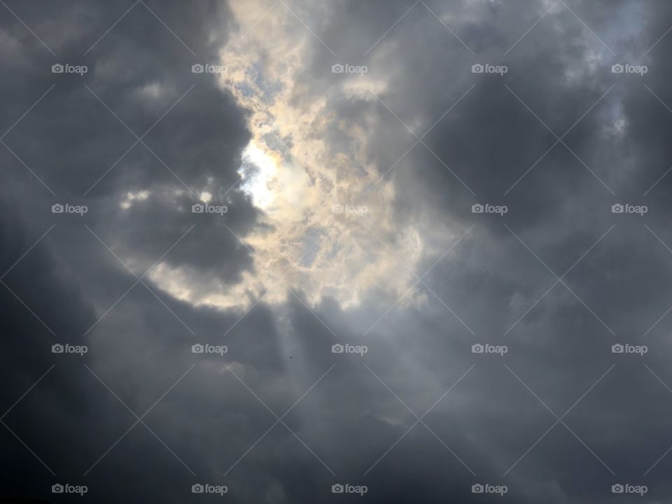 Sun rays bursting through gray sky clouds