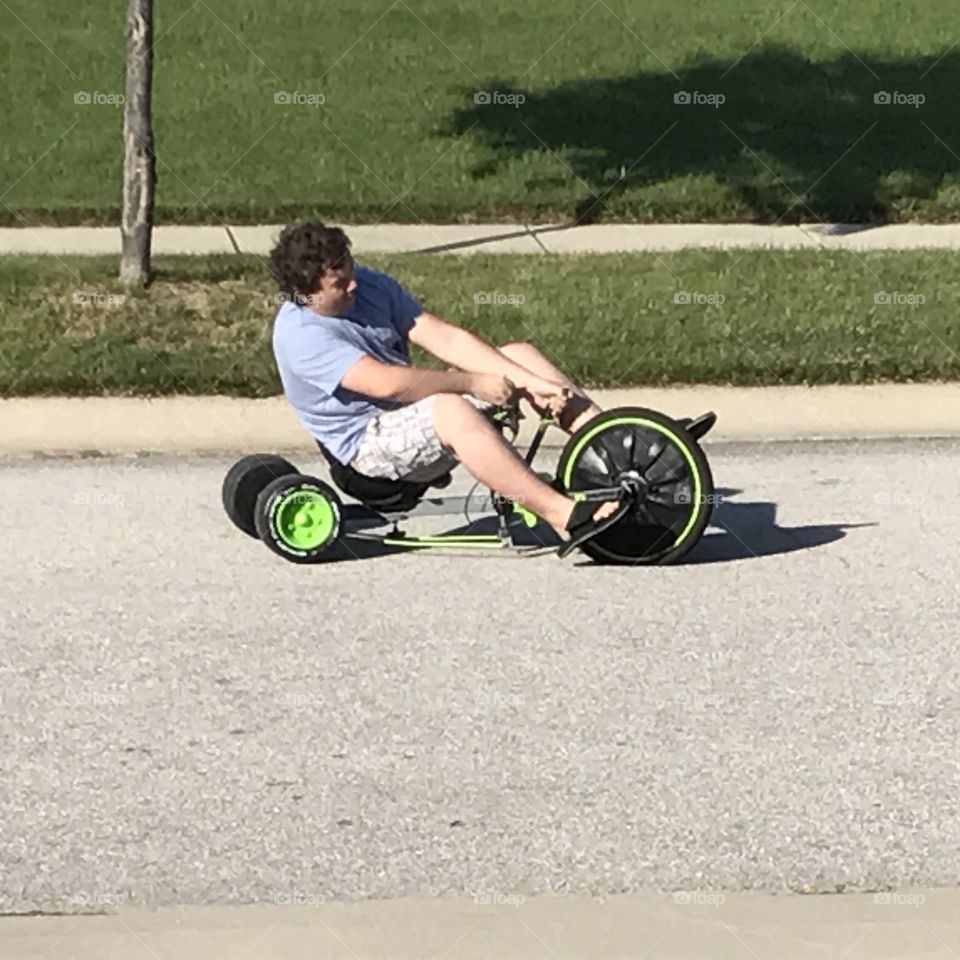 Grown man riding a boy's toy.