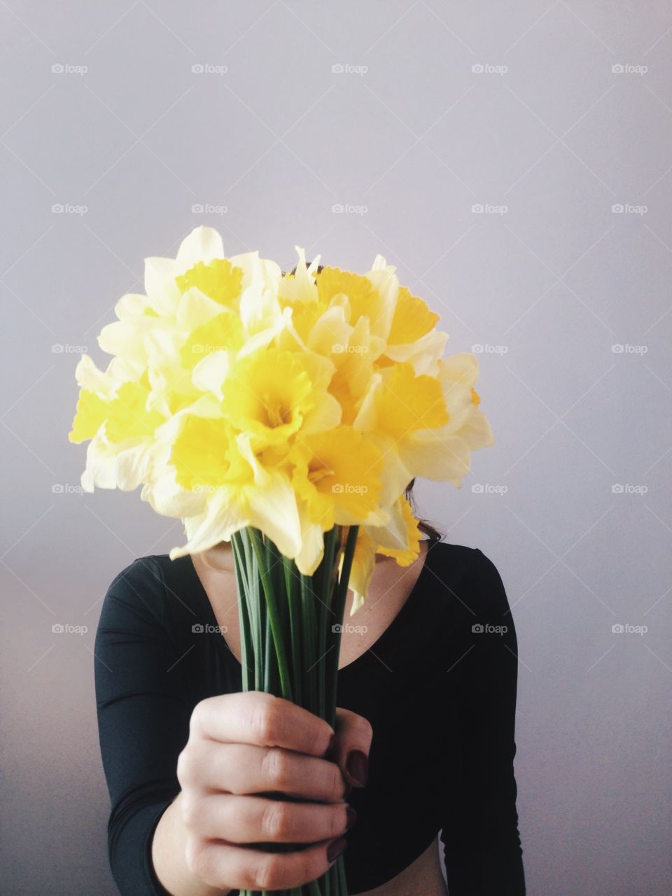 A person holding yellow flower bunch