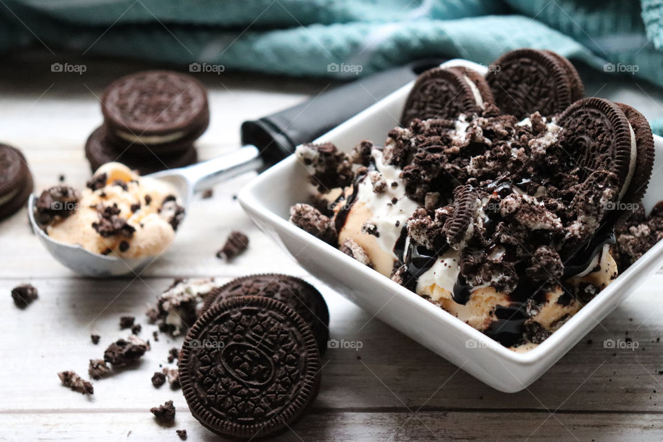 A bowl filled with ice cream, chocolate sauce and cookies