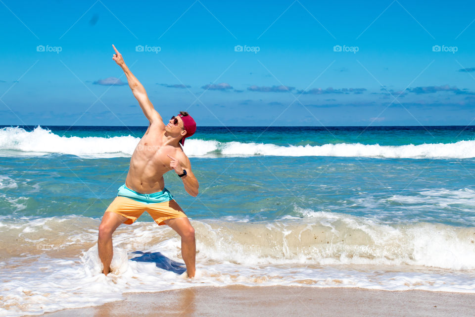 Guy posing on the beach as waves approach