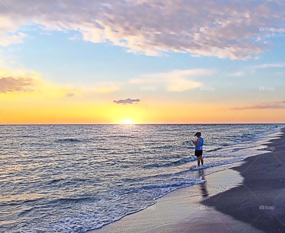 Woman enjoying a golden sunset from the beach.