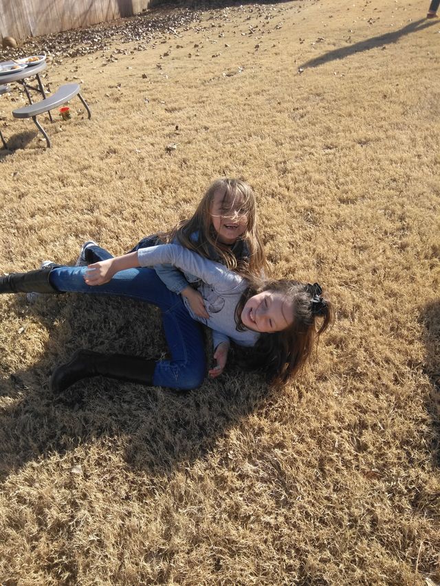 Cousins, Molly (8) & Madison (6) playing in the backyard on the fall grass. Two happy, healthy, active children pictured during a game of "tag."