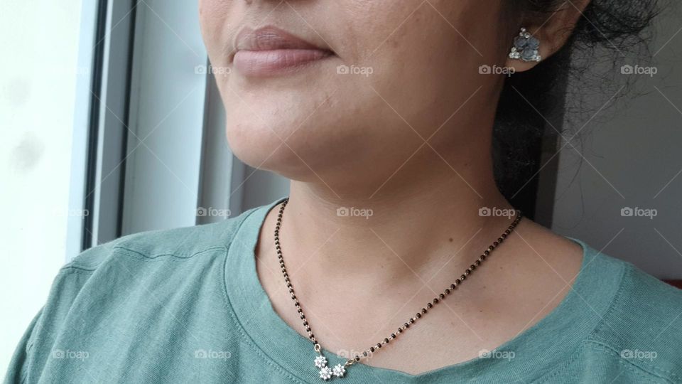 black beads along with dimond pendent on neck of indian women along with blue ear rings