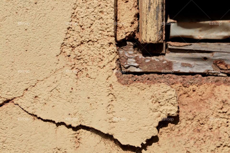 Peeling stucco and old window frame on derelict building, textural patterns 