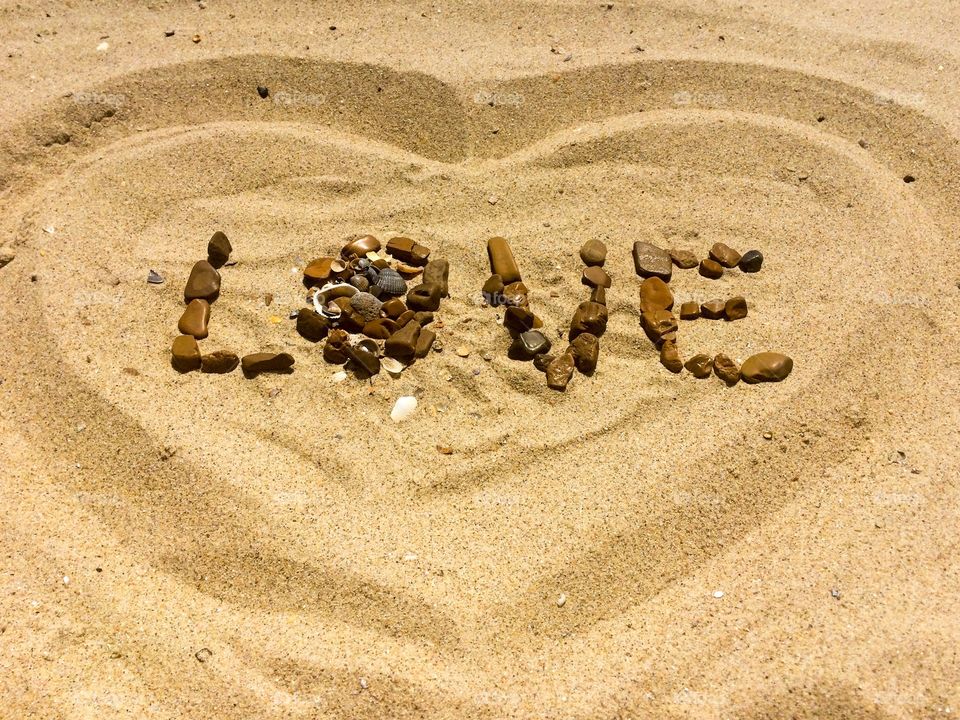 Love letter with stones and shells on a sand