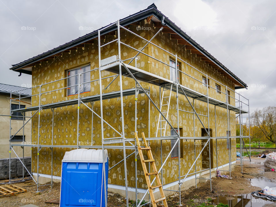 modern single family two store home under construction, enclosed with scaffolds