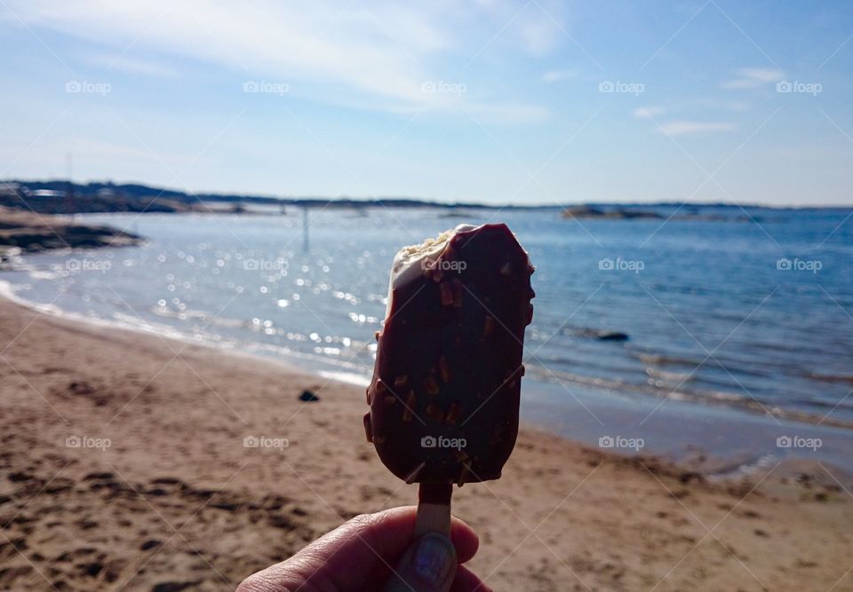 Hand holding ice lolly at beach