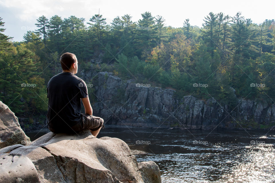 Morning meditation sitting high on the rocks by the river basking in the sun rays