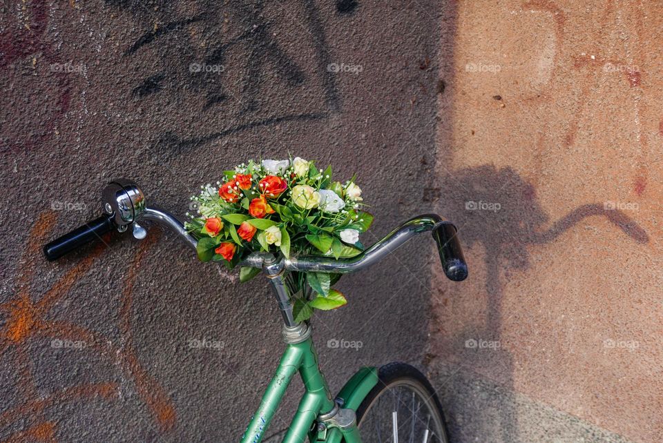 Vintage bicycle with flowers on handlebars leaning against wall