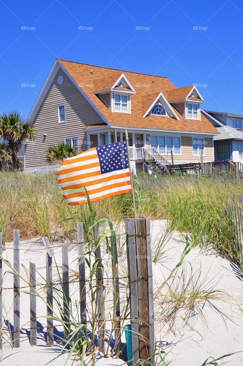 An American flag blows in the wind near a beach cottage. 