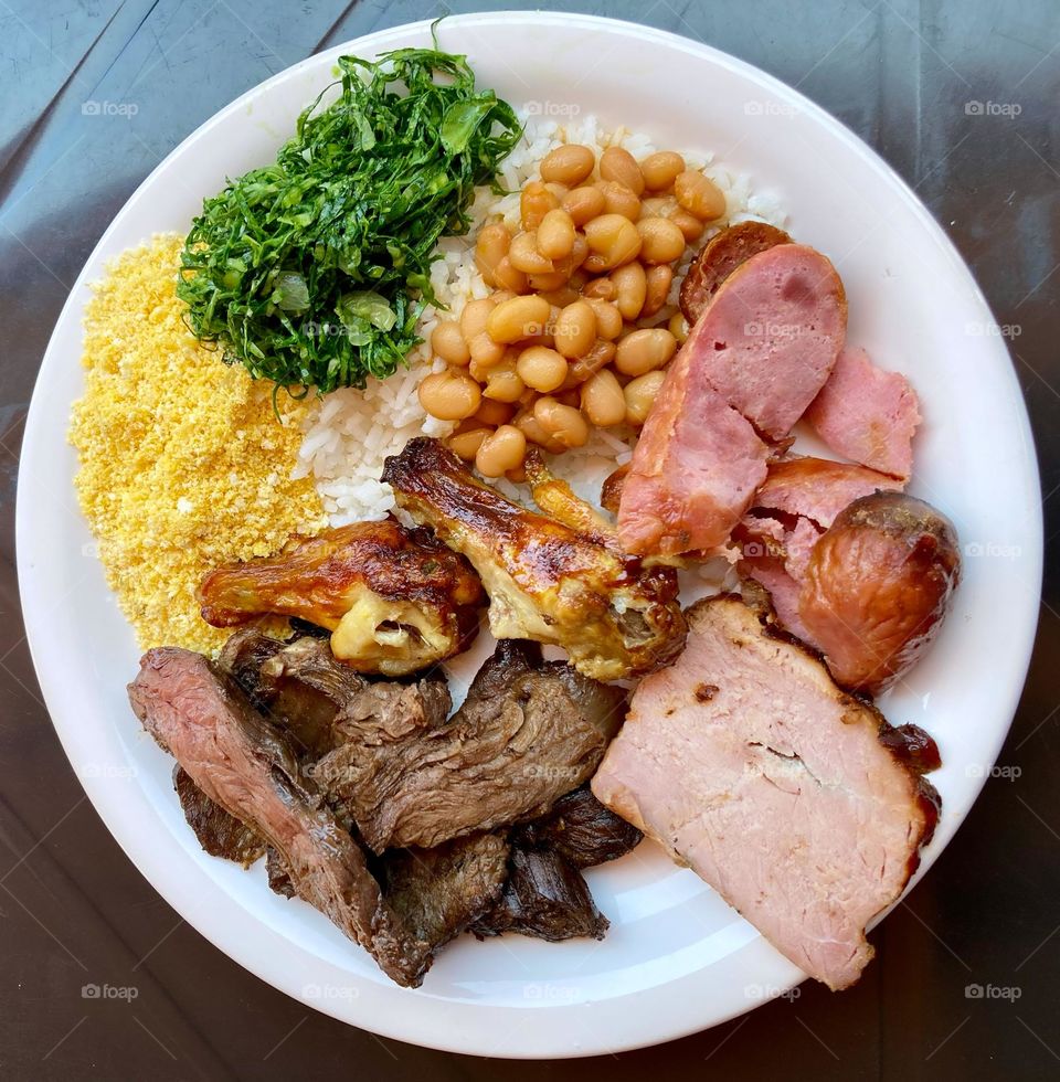 A typically Brazilian lunch: rice, beans, cabbage, farofa, sausage, ham, sausage and skirt steak. / Um almoço tipicamente brasileiro: arroz, feijão, couve, farofa, linguiça, pernil, linguiça e fraldinha.