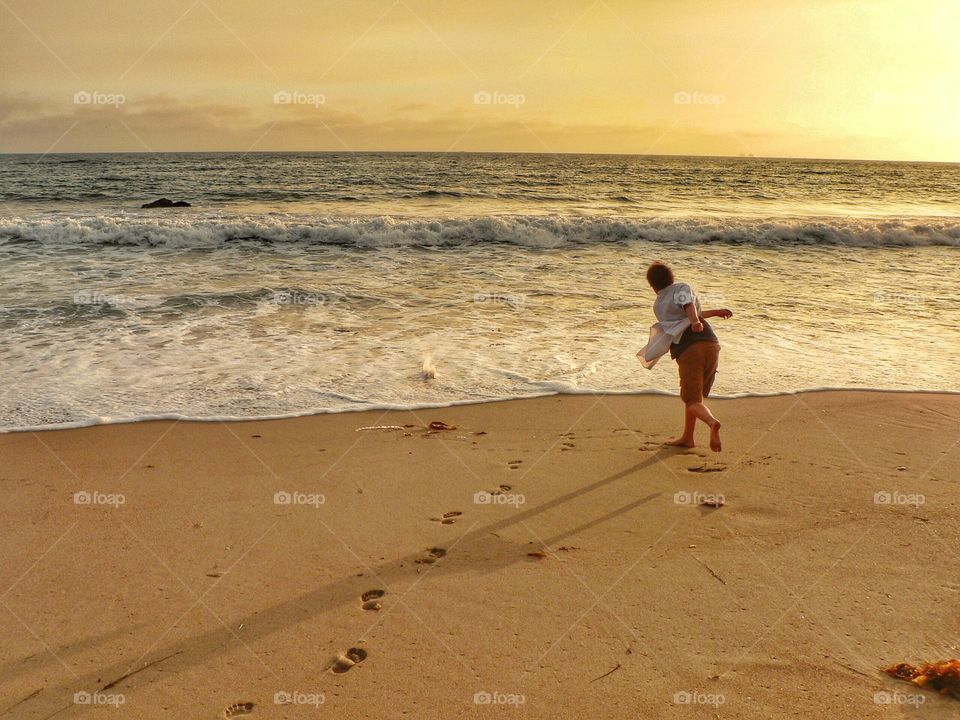 Boy skipping rocks into the ocean
