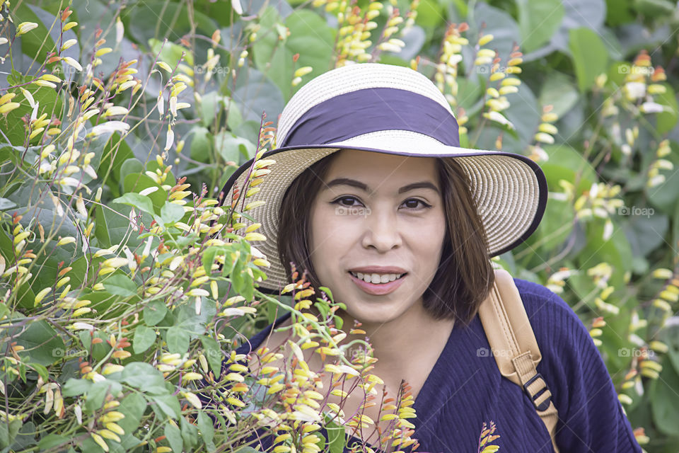 Portrait of Asean woman wearing a hat in the flower garden.