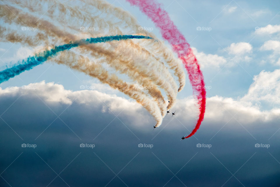 Red Arrows aerobatic display team flying across sky with red vapor trail