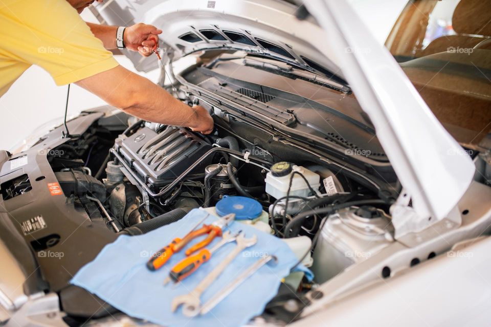 Mechanic checking oil levels on the car under the hood