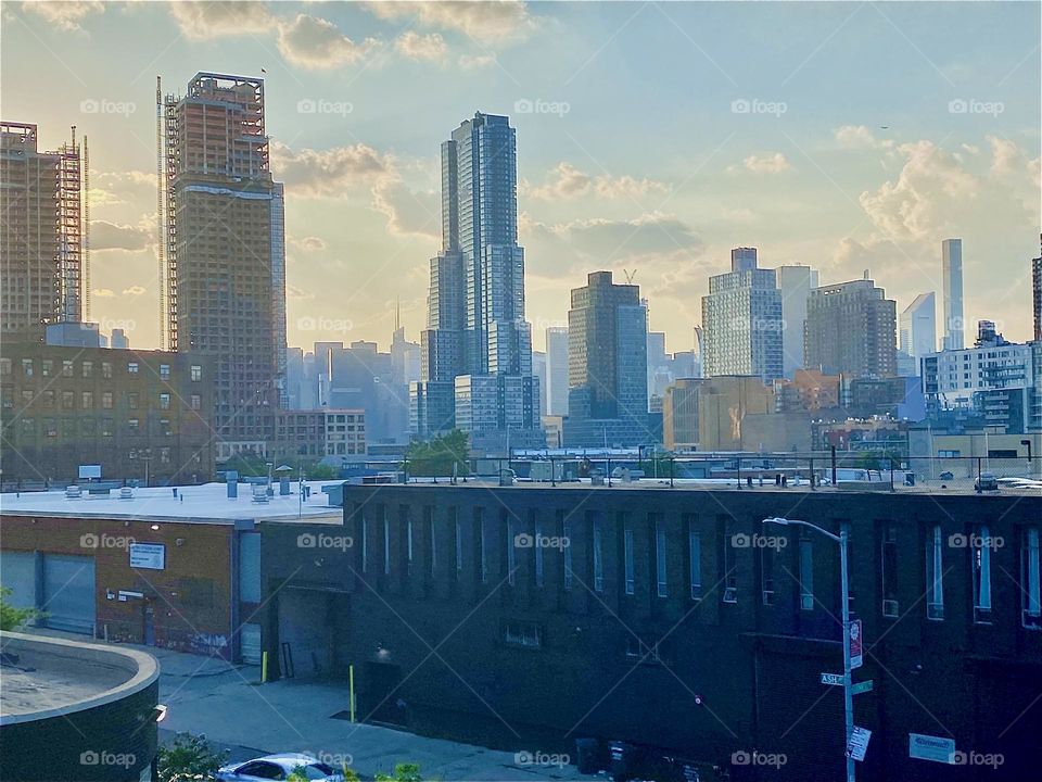 Seen from the staircase of the „Pulaski Bridge“ at half level there is a brownstone building nearby plus a tall building under construction with scaffolding, LIC as well as furthest back in the distance „Manhattan“. 2023. Hypnotic Productions