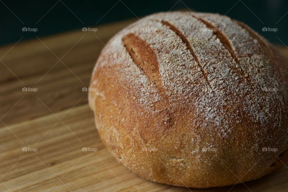 A freshly baked round loaf of sourdough bread on a wooden surface