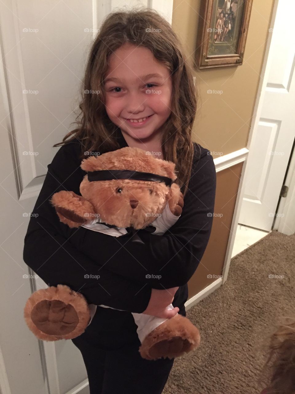 Little girl holding teddy bear in home