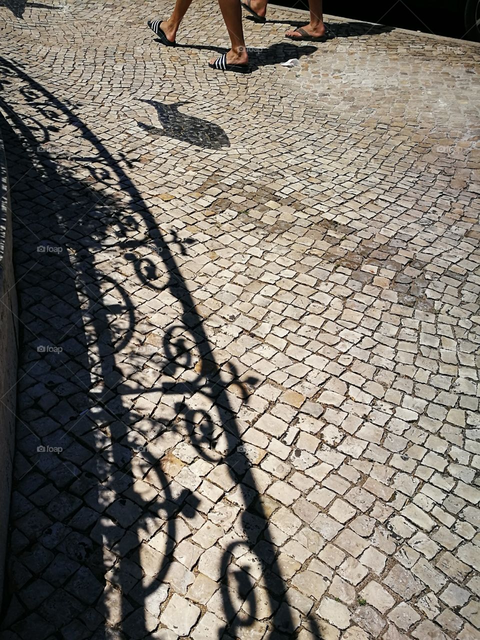 Shadows on portuguese pavement in a bright sunny day.