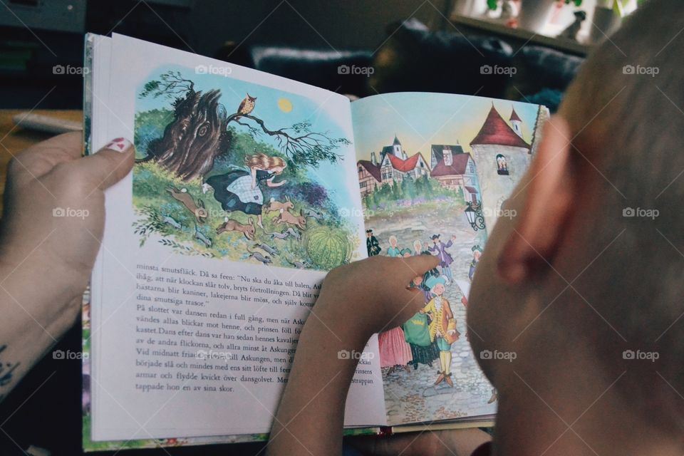 Boy reading book with his mother