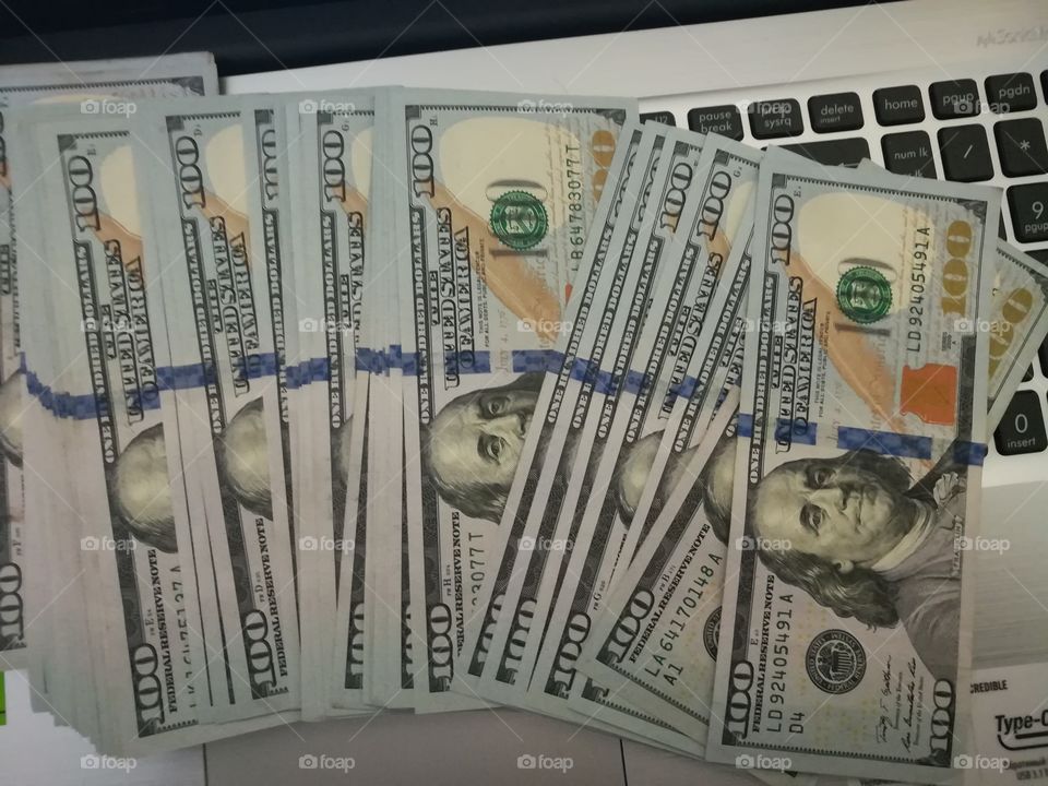 Пачка денег долларов на фоне ноутбука