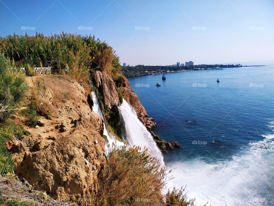 The beautiful waterfalls falling from the river to the sea. With amazing view on ships and seashore.