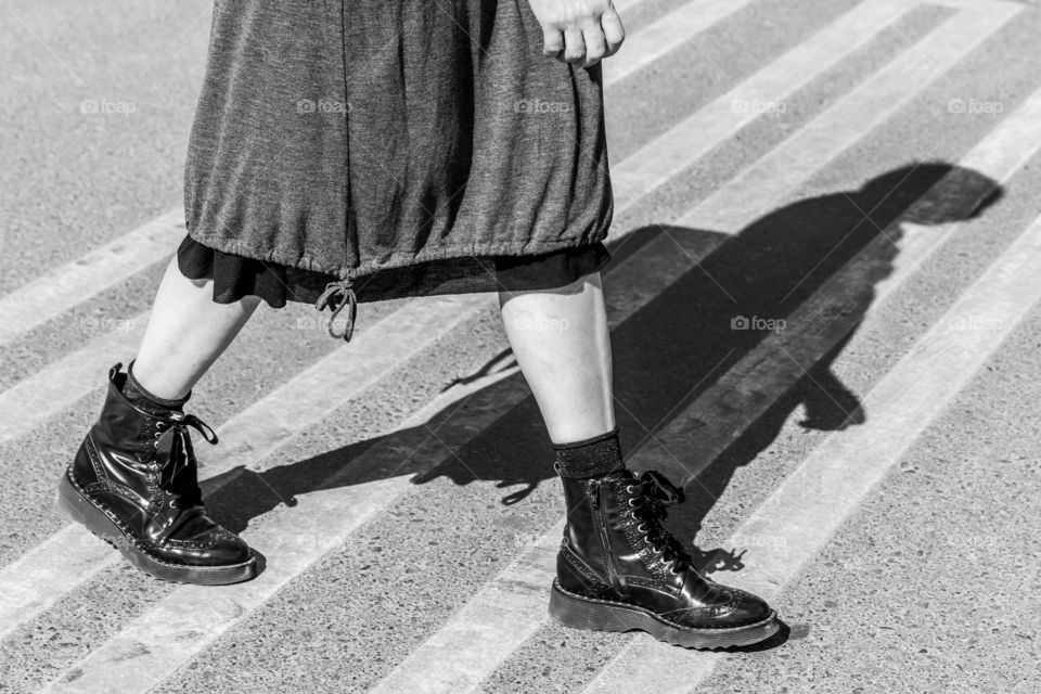 Woman walking on the pedestrian crossing, permanent shadow on the road