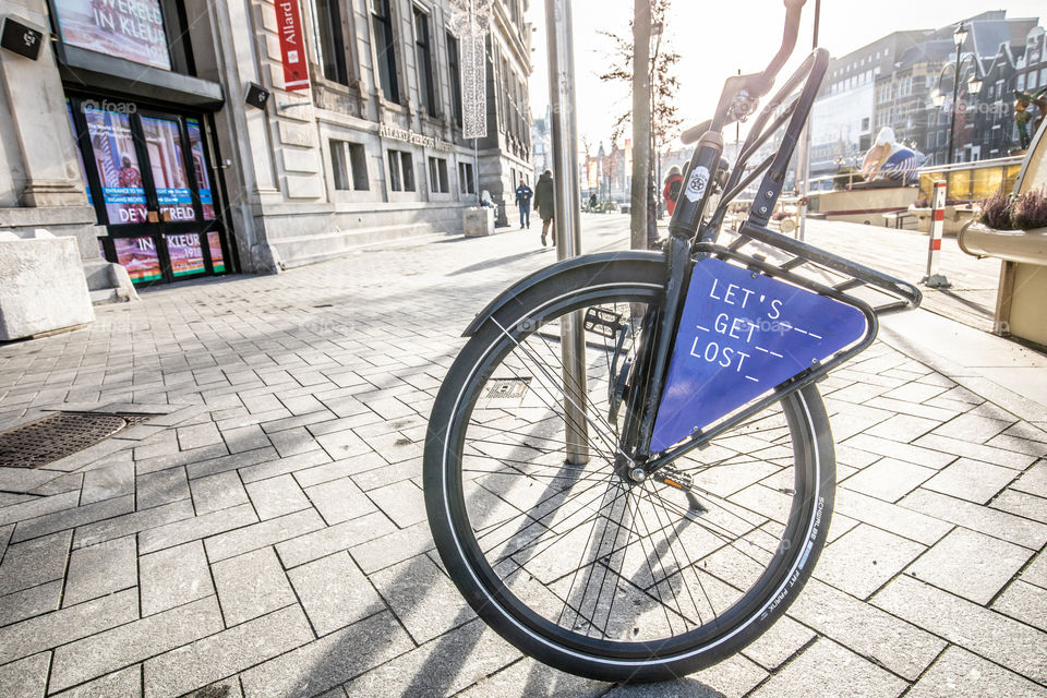 Bike parked in the city street with Let's Get Lost message on a sign.