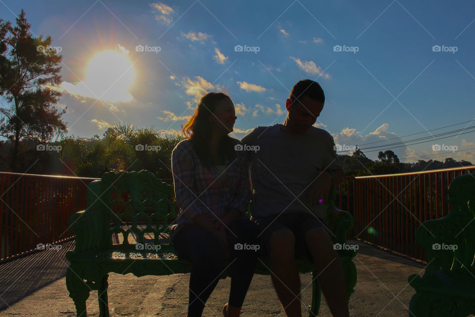 Couple sitting on park bench laughing at their jokes