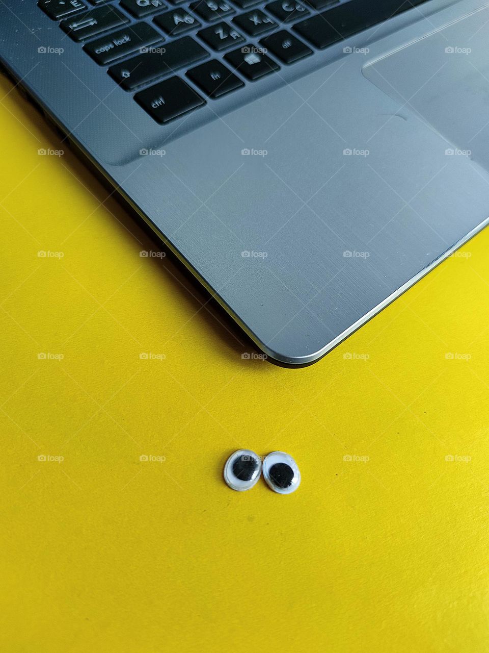 Yellow color.  On a yellow background, in contrast, lies the corner of a gray laptop.  Also on a yellow background are "eyes"