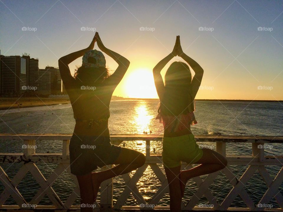 Two children in yoga pose at sunset