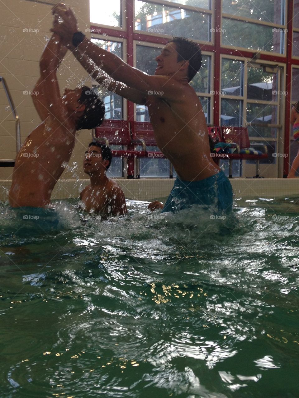 That boy can jump. Boys jumping up out of the pool to catch a football