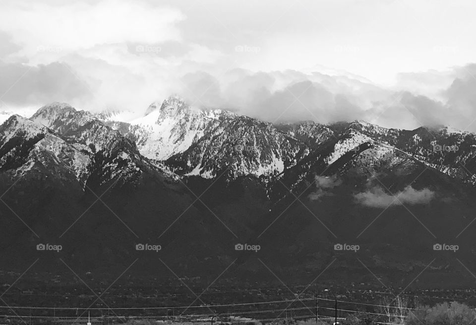 Beautiful mountain range. Clouds sitting atop and snow covered peaks. Black and white serenity.