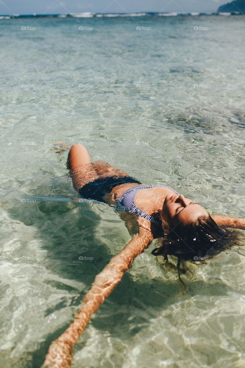 Girl relaxes in shallow ocean water.
