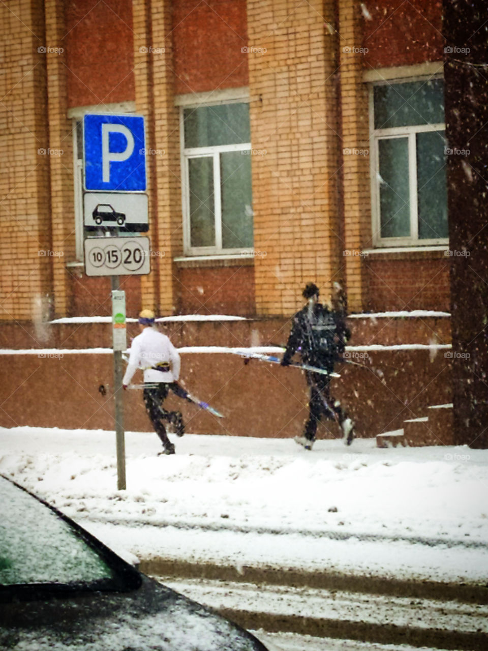 Two skiers running along a snowy street