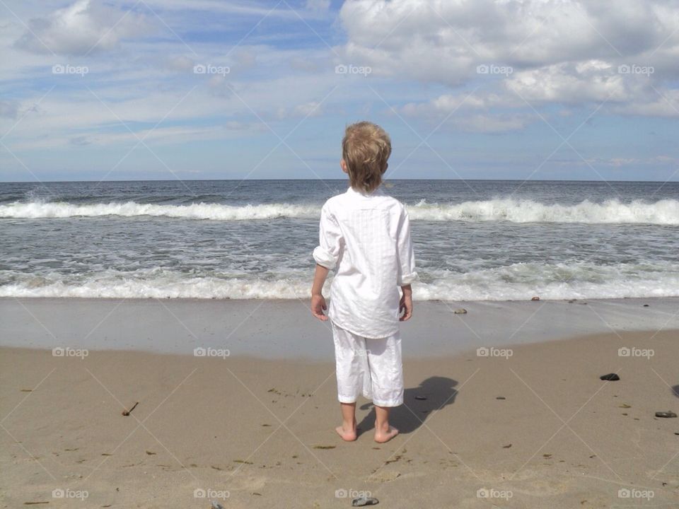 Boy on the beach looks at sea