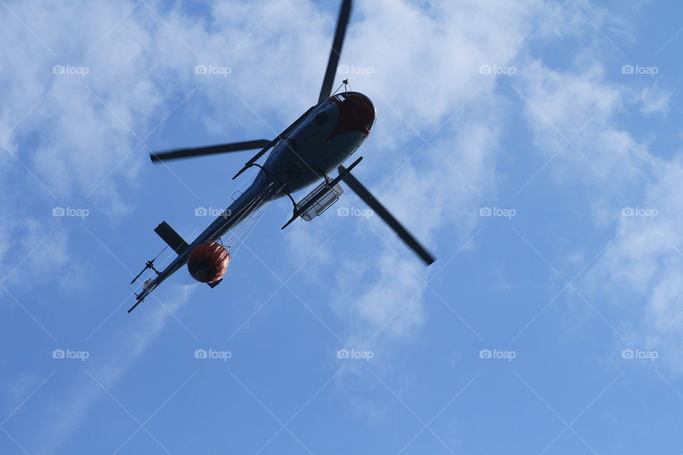 A canadair and a helicopter collect water and fly to the mountains to put out a big fire in Liguria.